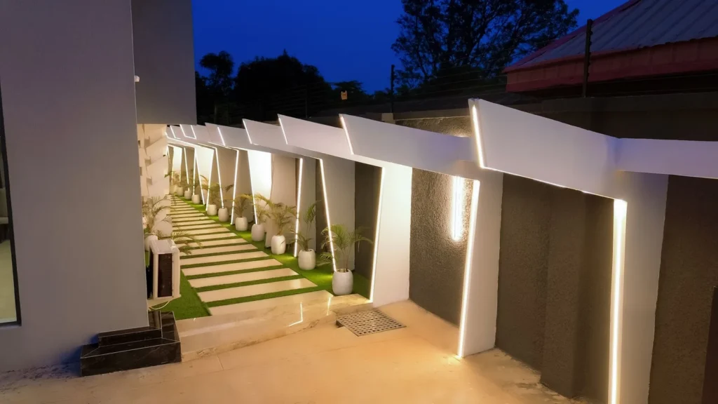 Garden walkway with lit white portals and potted palms at night