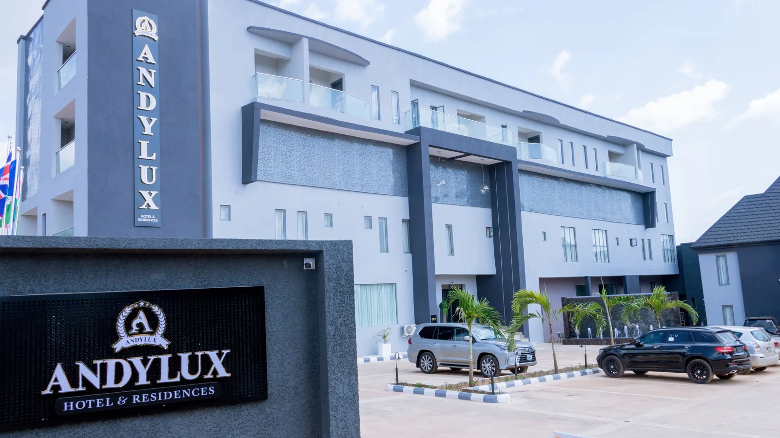 The Andylux building by day with its tall dark sign tower and glass balconies