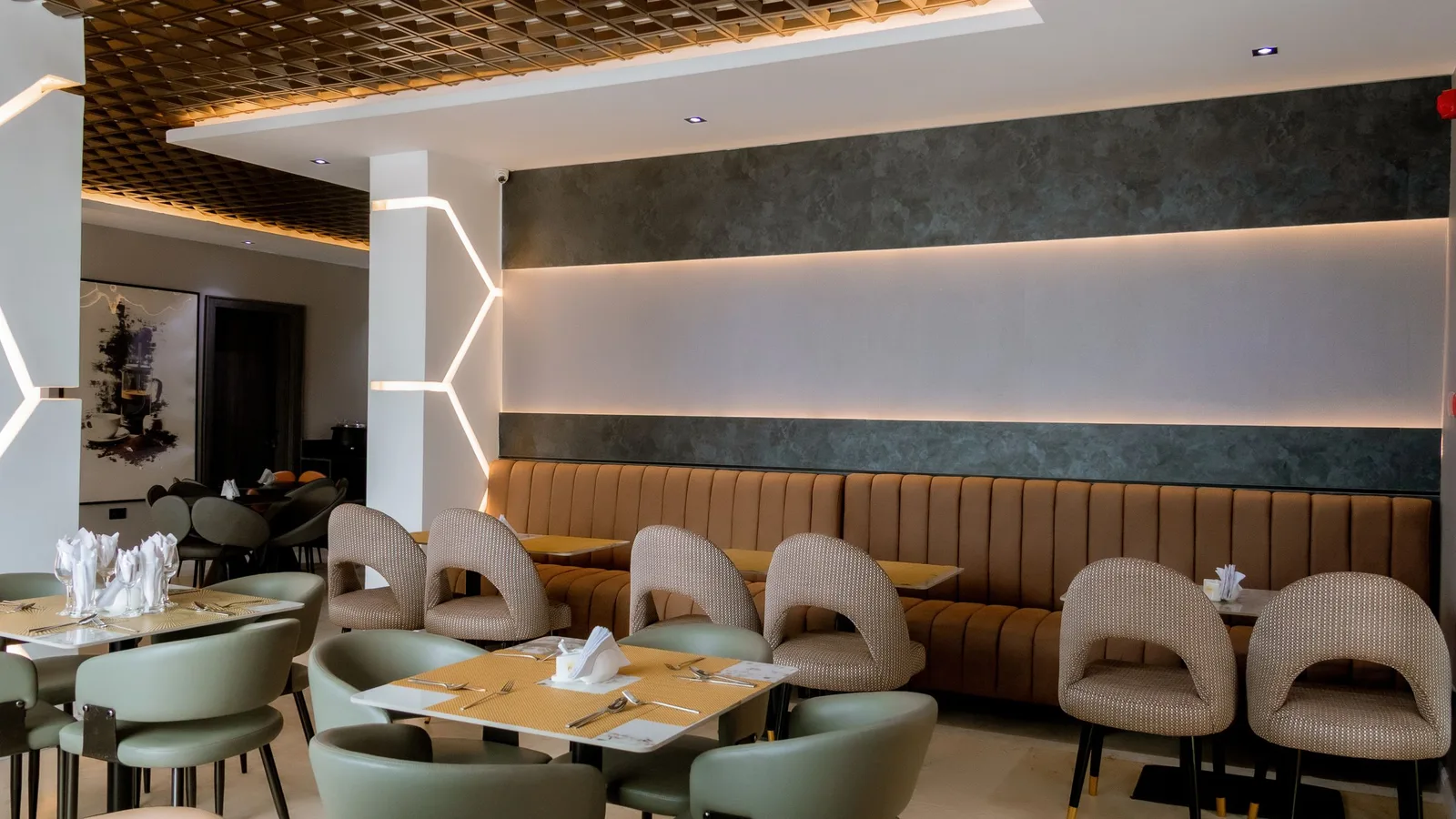 Restaurant with tan banquette seating, sage leather chairs and lit wall panels