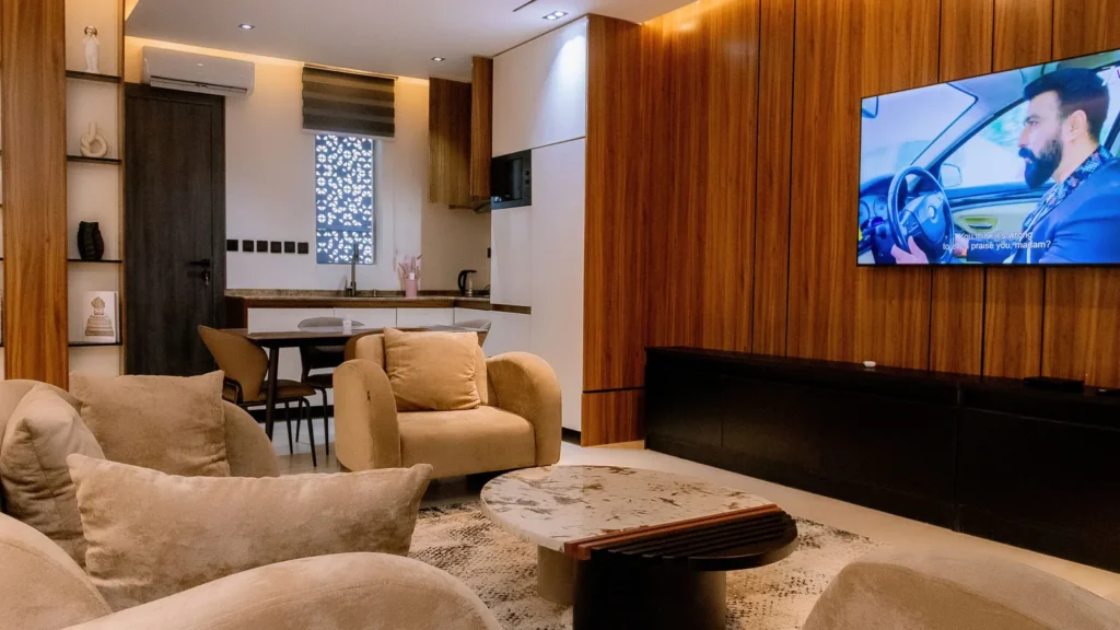 Apartment living room with sofas, wood-panelled TV wall and an open kitchen