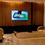 Suite lounge with velvet sofas facing a wall-mounted TV on walnut panelling