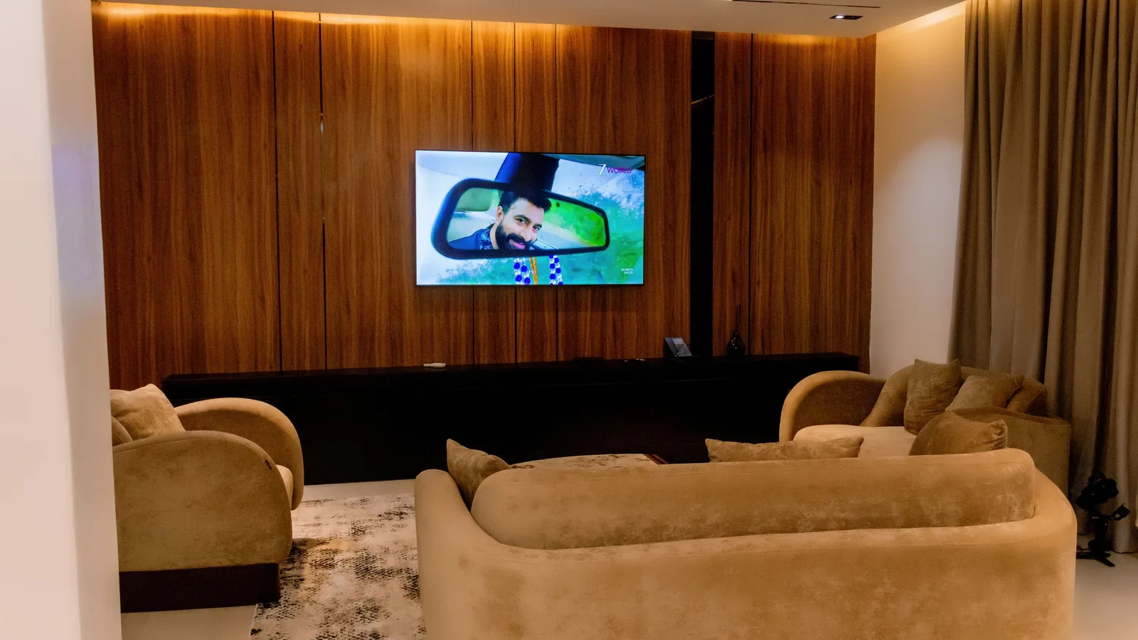 Suite lounge with velvet sofas facing a wall-mounted TV on walnut panelling